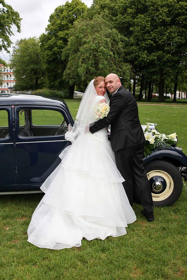 COUPLE DE MARIES DEVANT UNE TRACTION NOIR DANS UN PARC